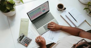 Self-employed person managing their business finances on a laptop at a home desk