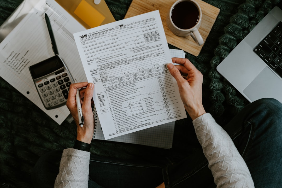 Tax forms, calculator and laptop on a desk, representing HMRC's automatic sign-up for MTD for Income Tax